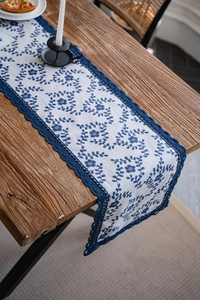 Detailed view of navy floral embroidery on white linen table runner with lace edges