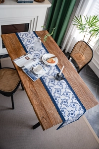 Detailed embroidery of navy blue flowers on white cotton linen table runner with lace edge