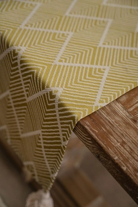 Close-up of mustard yellow and beige geometric woven table runner with decorative tassels