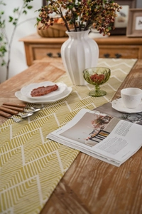 Close-up of yellow and green geometric jacquard table runner with white tassel details