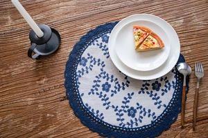Detailed view of round table mat with navy floral pattern and crochet lace edge