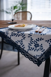 Detail of floral embroidery and crochet lace edge on a rustic beige linen table runner