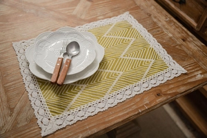Close-up of yellow geometric table runner with white lace edges on a wooden surface