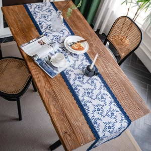 Floral print cotton linen table runner with navy blue lace edges on a wooden table
