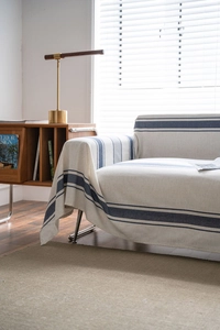 Detailed texture of navy blue striped cotton throw blanket on a cozy sofa
