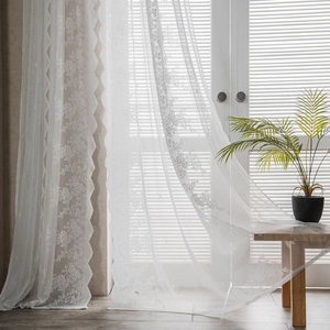 White vintage lace curtains with delicate floral embroidery and wavy edges for windows