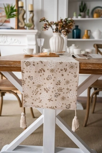 Dettaglio di un runner beige con stampe di soffioni ed eleganti frange decorative