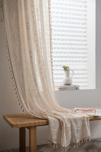 Détail du rideau en dentelle au crochet bohème avec motifs géométriques et pompons