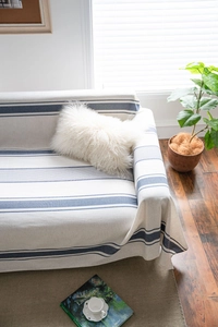 Detail of navy blue striped cotton linen sofa cover with soft decorative white plush pillows