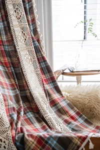 Detailed close-up of vintage plaid curtains with crochet lace and white fringe tassels