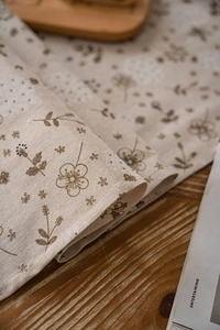 Dettaglio della stampa di dente di leone su runner in lino beige con trama rustica
