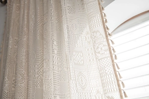 Gros plan détaillé du rideau en dentelle au crochet avec motifs géométriques et franges