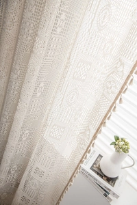 Gros plan de rideaux en dentelle au crochet géométrique avec motifs floraux et pompons