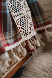 Detail of red and brown plaid curtain with exquisite white crochet lace and tassel fringe