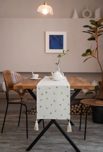 Close-up of lemon print table runner with handmade cotton tassels on wooden table