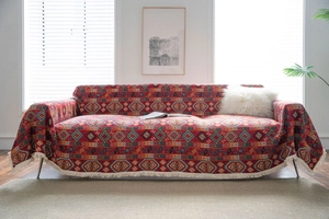 Close-up of red bohemian sofa cover with intricate geometric jacquard and white tassels