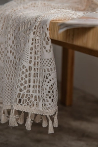 Gros plan du rideau au crochet crème avec motif géométrique ajouré et bordure à franges