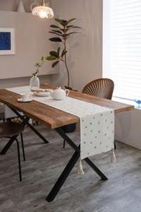 Close-up of a modern pastoral table runner with lemon prints and cotton tassels on wood