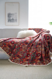 Close-up detail of ethnic red sofa cover with bohemian patterns and white fringe