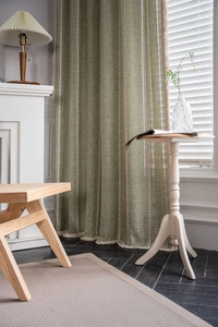 Detail of green striped curtains featuring heart patterns and soft fringe trim