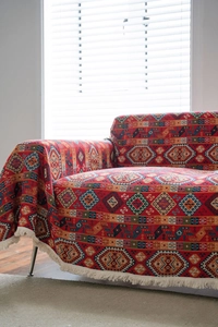Detail showing red bohemian jacquard sofa throw with geometric patterns and white fringe