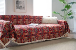 Detail view of red ethnic jacquard sofa throw cover with geometric patterns and white tassels