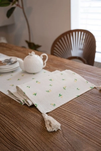 Detail of lemon print table runner with tassels on a rustic dark wood dining table