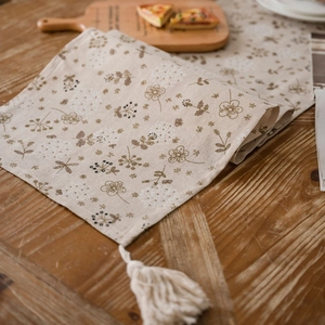 Runner da tavolo con stampa di denti di leone e nappe su un tavolo da pranzo rustico