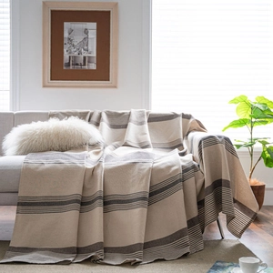 Minimalist striped coffee brown sofa cover with decorative tassels on a gray sofa