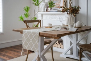 Close-up of geometric quatrefoil pattern on beige table runner with elegant fringe trim