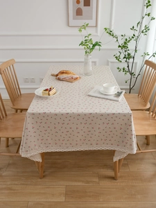Close-up of pink cherry print tablecloth with elegant beige lace border and linen texture
