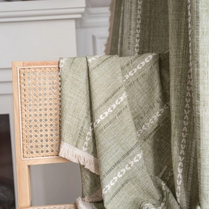 Green rustic striped embroidered curtain with wheat patterns and cream tassels on wood chair
