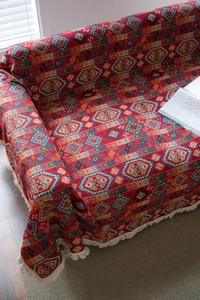 Detail of red Kilim style knitted sofa cover with geometric patterns and white tassels