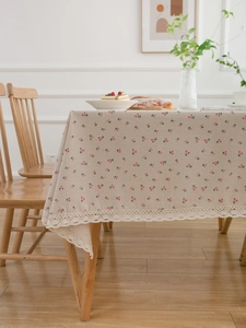 Detail of linen tablecloth featuring cherry print and delicate white crochet lace trim