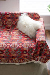 Macro shot of ethnic jacquard sofa cover with red geometric patterns and fringe detail