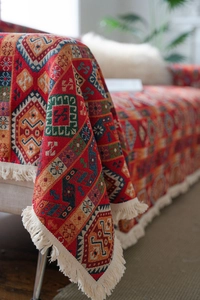 Detail of red bohemian woven sofa cover featuring geometric patterns and ivory fringes