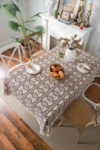 Close-up of geometric jacquard tablecloth with bohemian fringe in warm dining scene