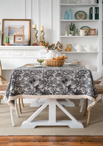 Detail of Toile de Jouy tablecloth with black and white palm trees and beige fringe