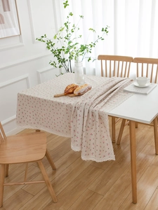 Detail of beige table cloth featuring pink cherry print and delicate white lace edges