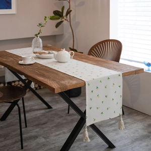 Linen table runner with lemon prints and tassels on a wooden dining table