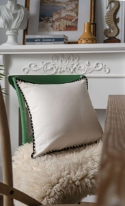 Close-up of minimalist cream table runner with black pom-pom trim on a vintage chair