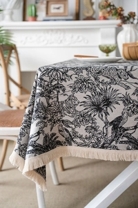 Close-up of black animal print jacquard tablecloth with elegant cream tassel fringe edges