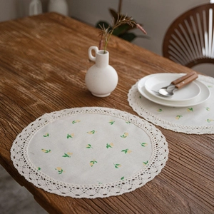 Floral embroidered round cotton placemats with delicate lace edges in a rustic home setting