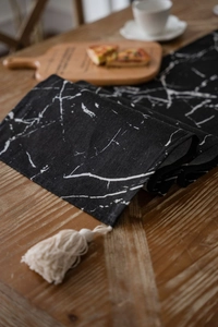 Detail of modern marble print table runner with white decorative tassels on wood table