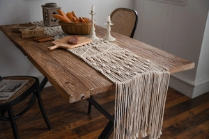Detail of bohemian hand-woven table runner with intricate geometric patterns and long tassels