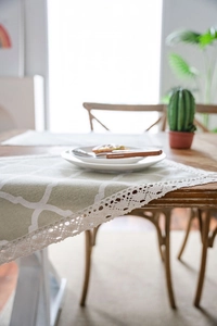 Close-up of light green geometric quatrefoil table runner with white lace border details