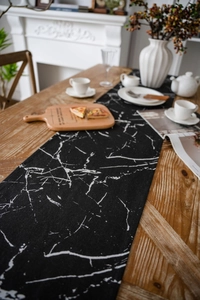 Close-up of marble pattern table runner with black base and white veins on wooden table