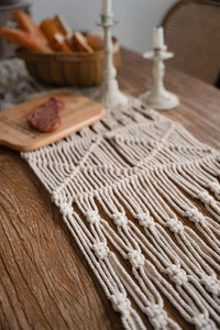 Detail of bohemian macrame table runner featuring hand-woven cotton patterns and tassels