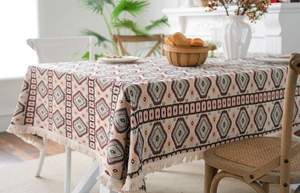 Close-up of bohemian geometric woven tablecloth with red diamond patterns and white tassels
