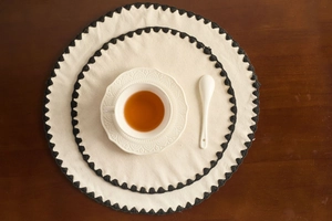 Close-up of minimalist cream table runner with black crochet scalloped lace edge detail